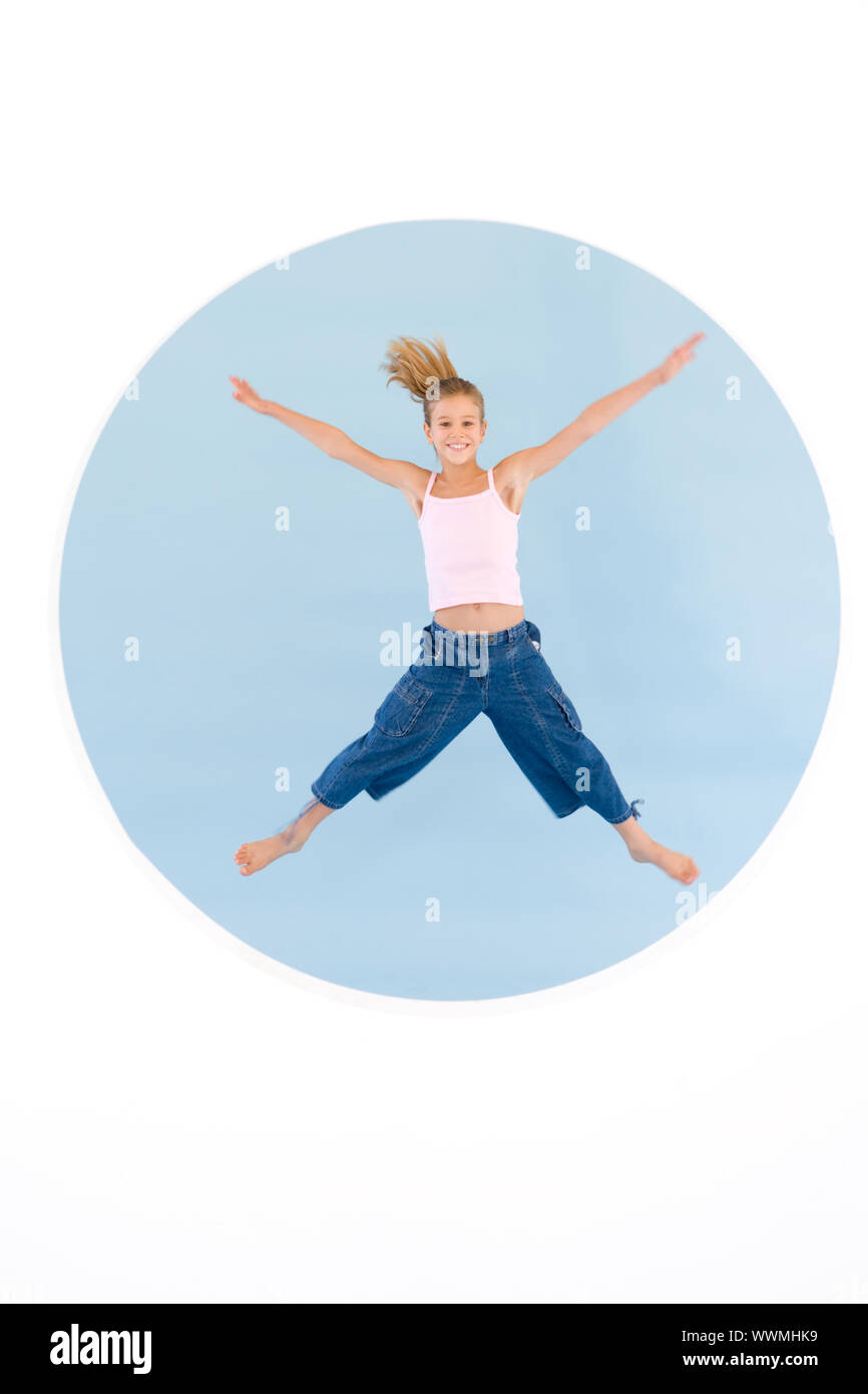 Young girl jumping with arms out smiling Stock Photo