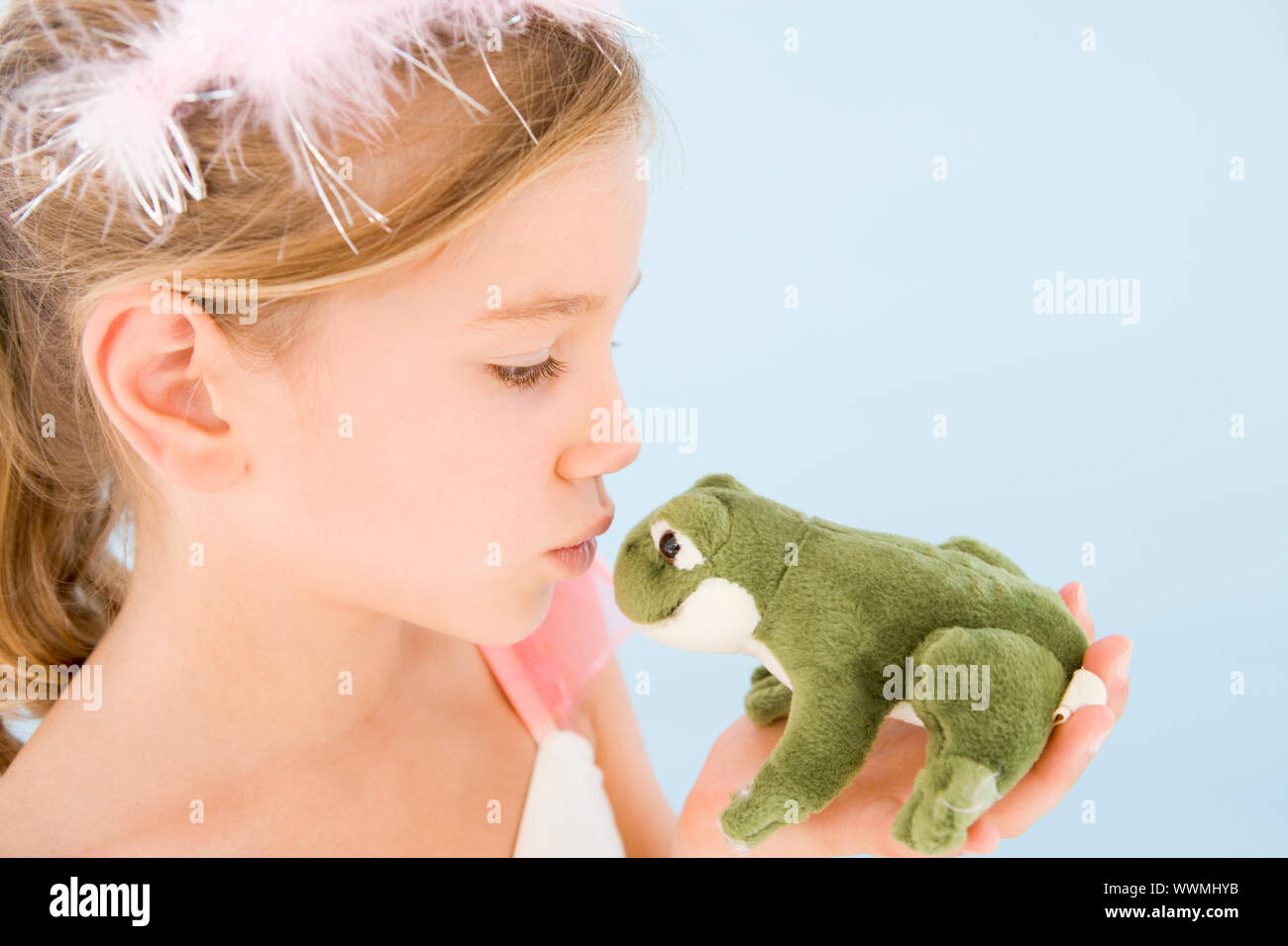 Young girl in princess costume kissing plush frog Stock Photo