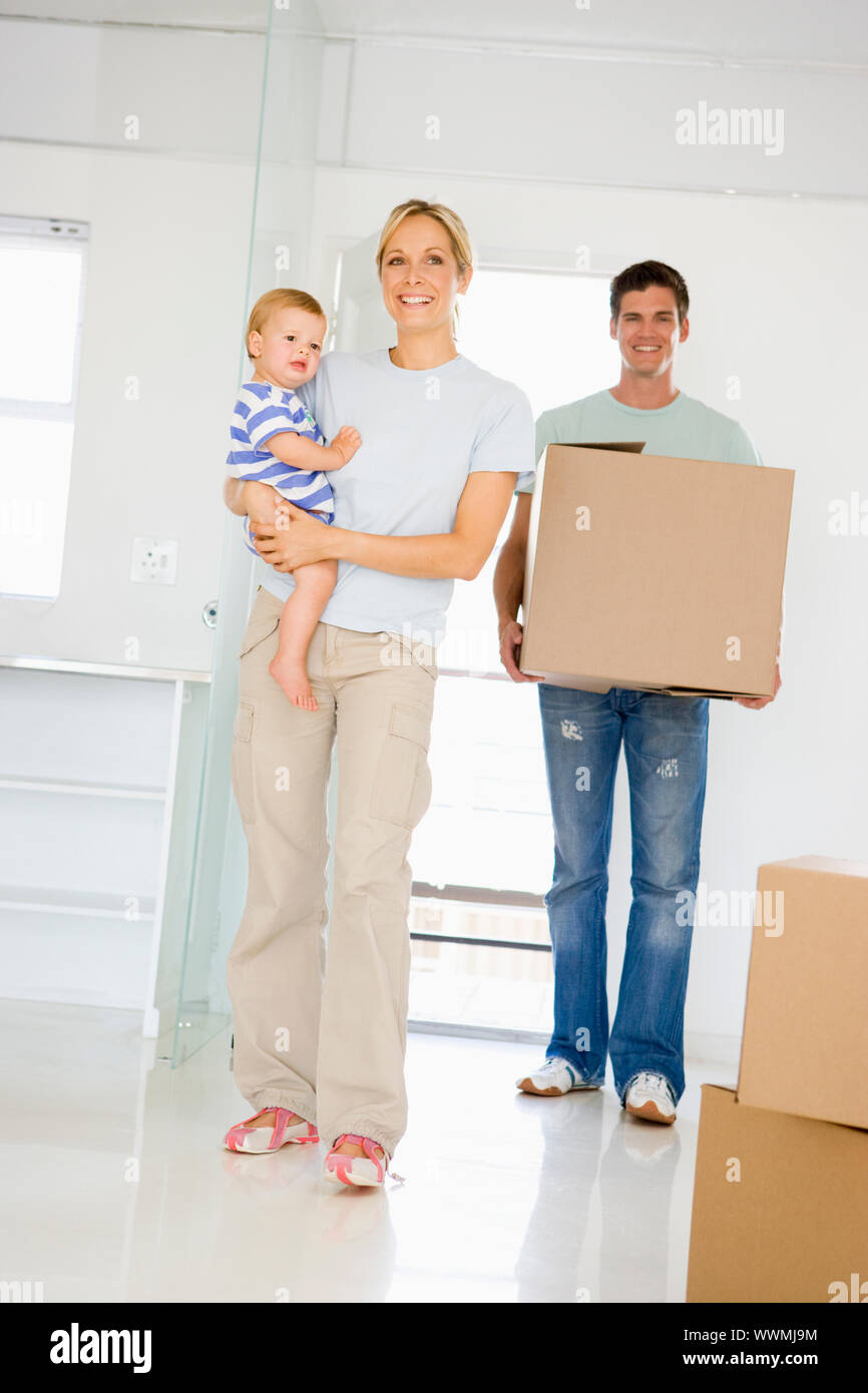 Family with box moving into new home smiling Stock Photo - Alamy