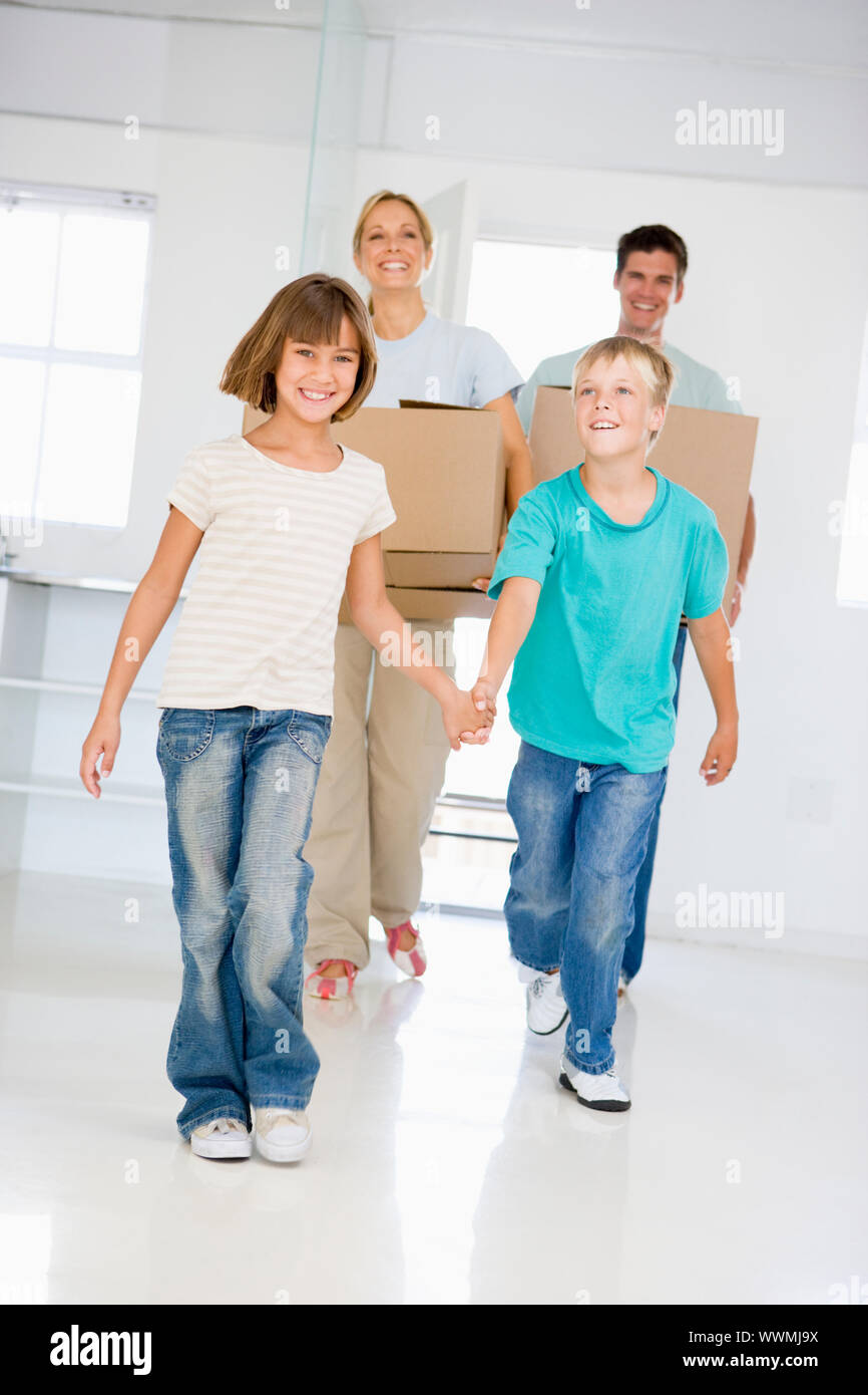 Family with boxes moving into new home smiling Stock Photo - Alamy