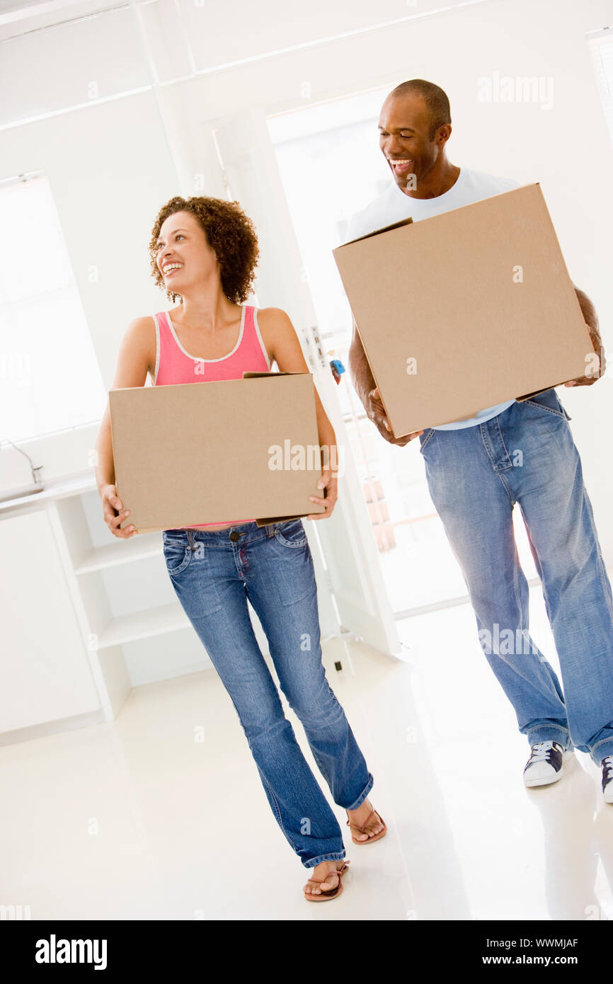 Couple with boxes moving into new home smiling Stock Photo - Alamy