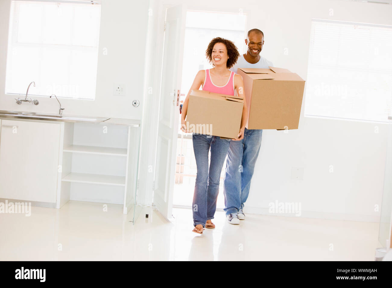 Couple with boxes moving into new home smiling Stock Photo - Alamy