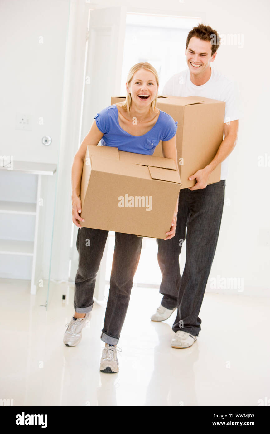 Couple with boxes moving into new home smiling Stock Photo - Alamy