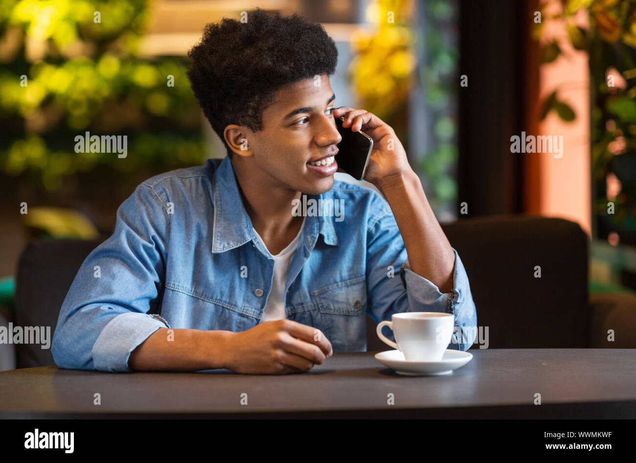 Young afro guy talking on smartphone, looking aside Stock Photo
