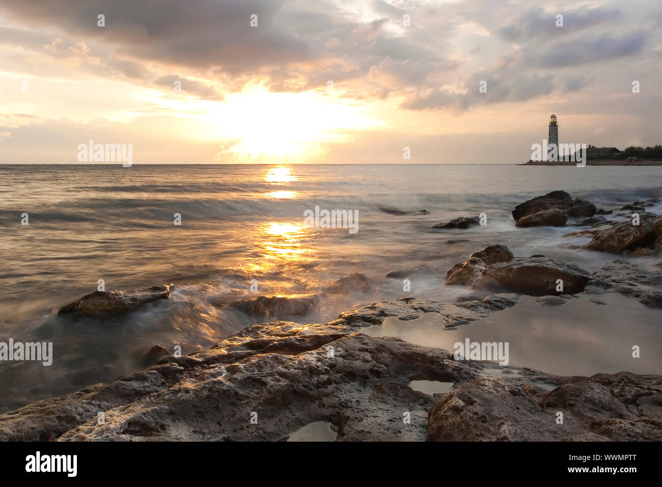Beautiful rocky sea beach at the sunset with the lighthouse Stock Photo ...