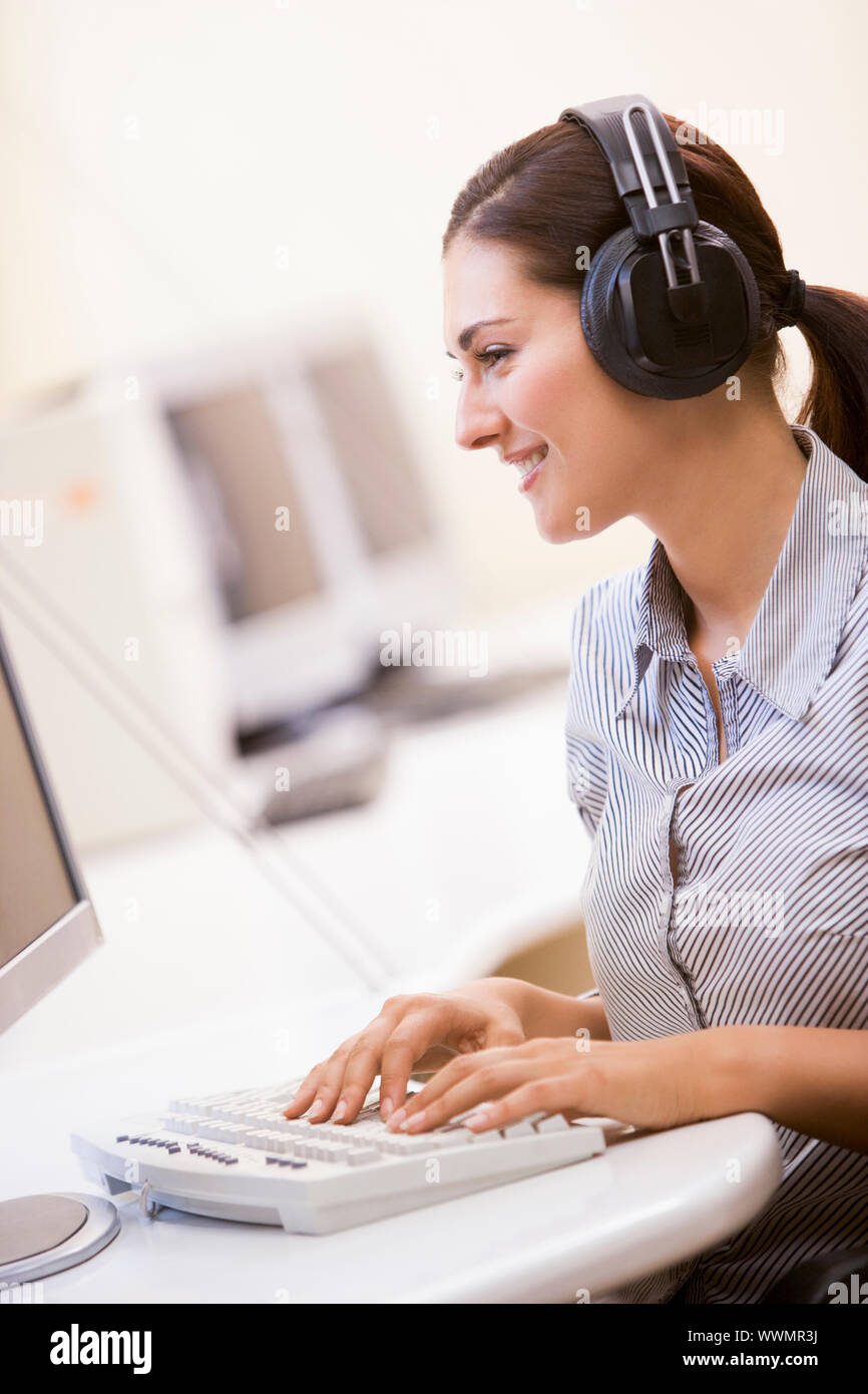 Woman wearing headphones in computer room typing and smiling Stock ...
