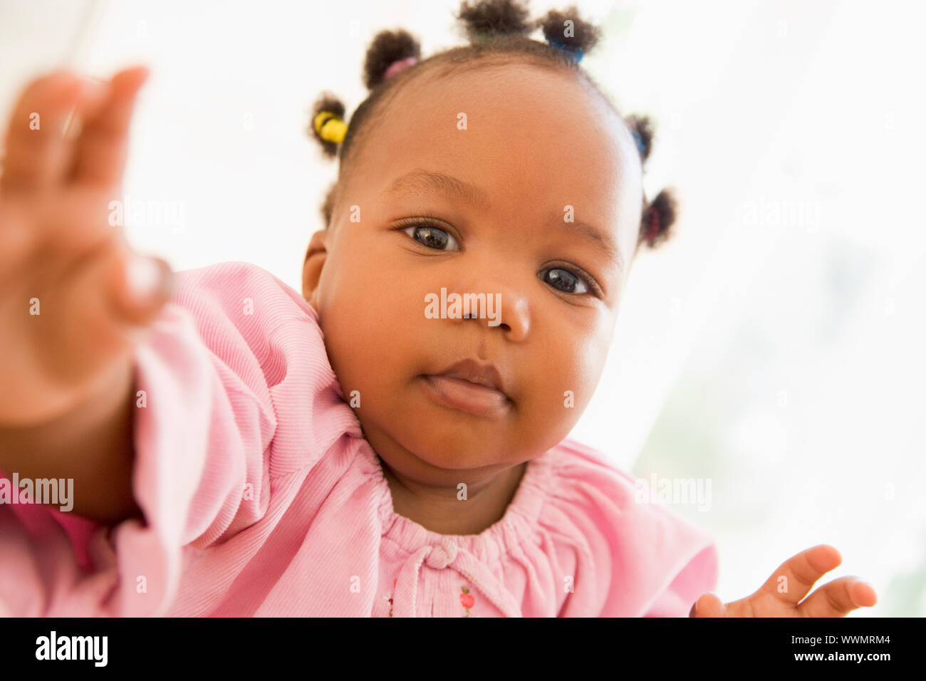 Baby indoors reaching hand out Stock Photo