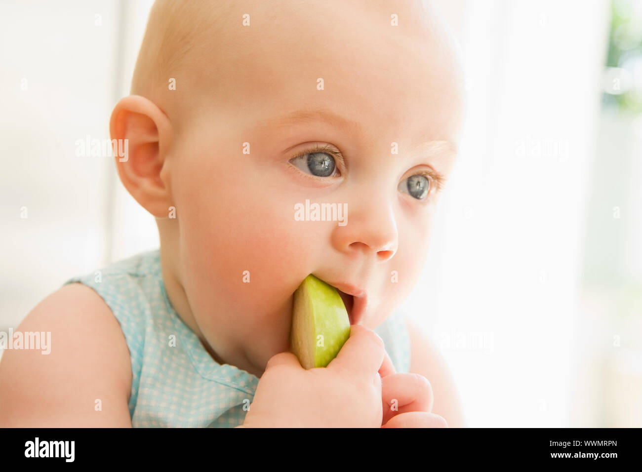 Baby eating apple indoors Stock Photo