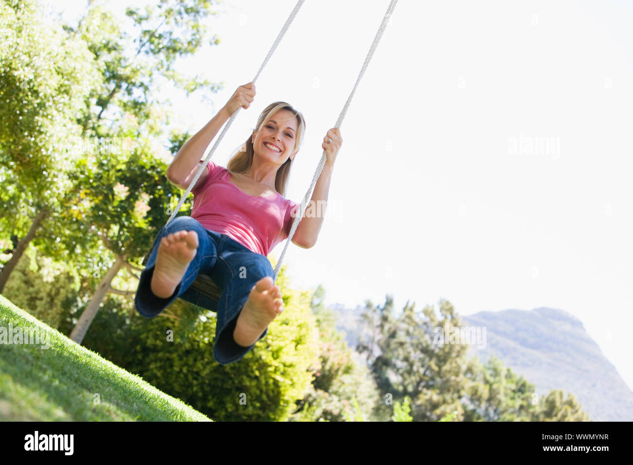 Woman on tree swing smiling Stock Photo