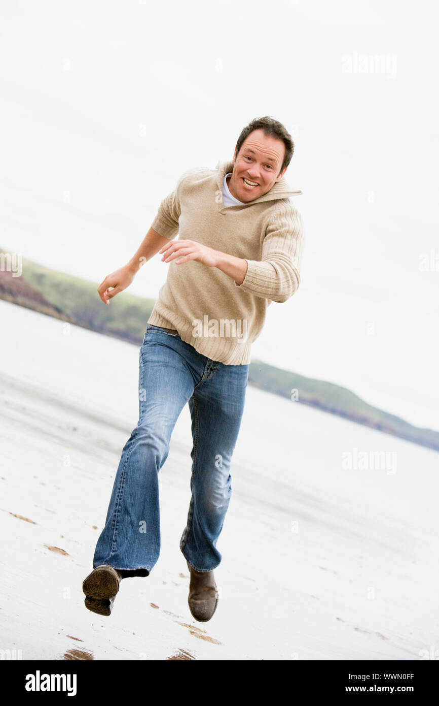 Man running on beach smiling Stock Photo