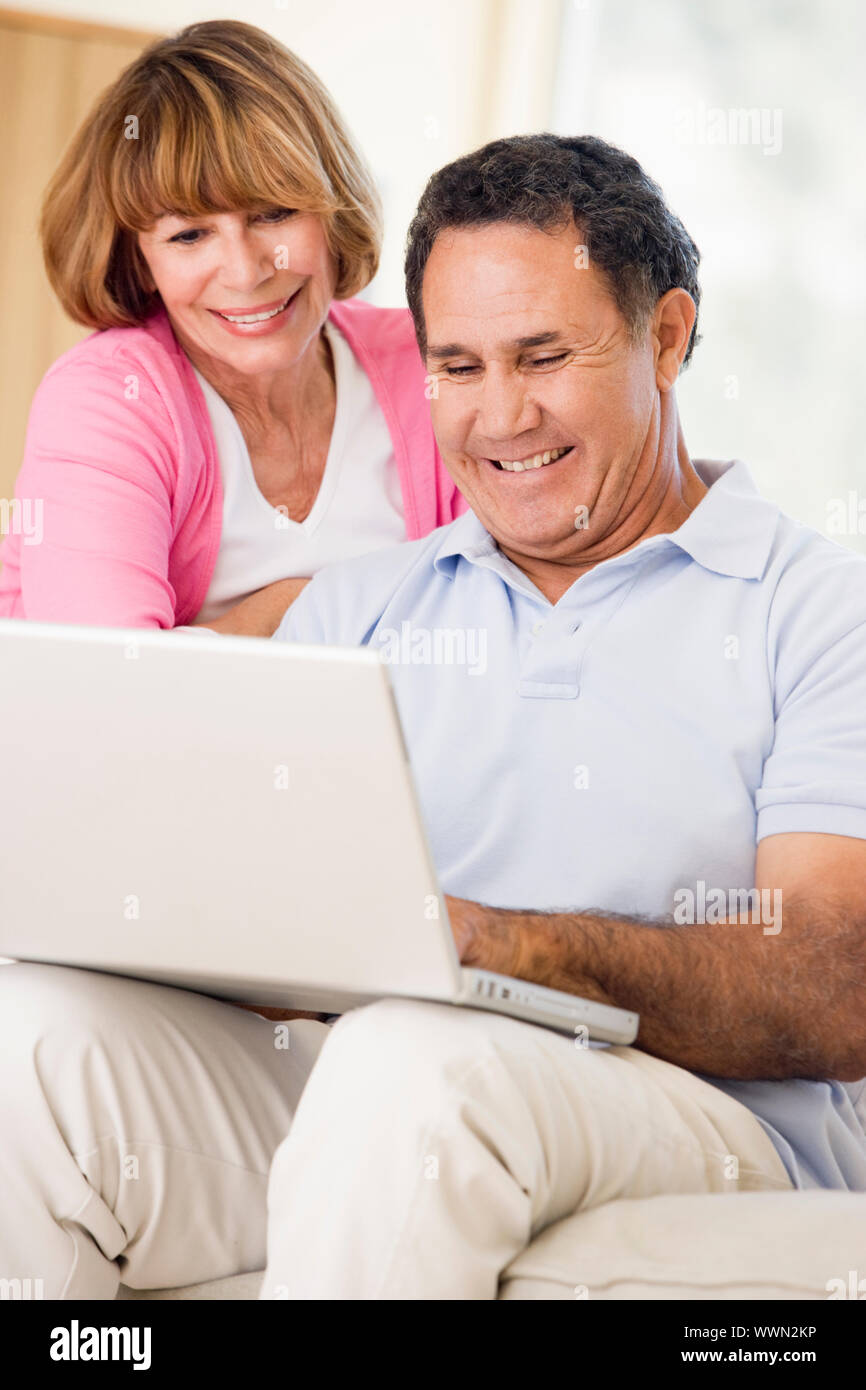 Couple in living room with laptop smiling Stock Photo - Alamy