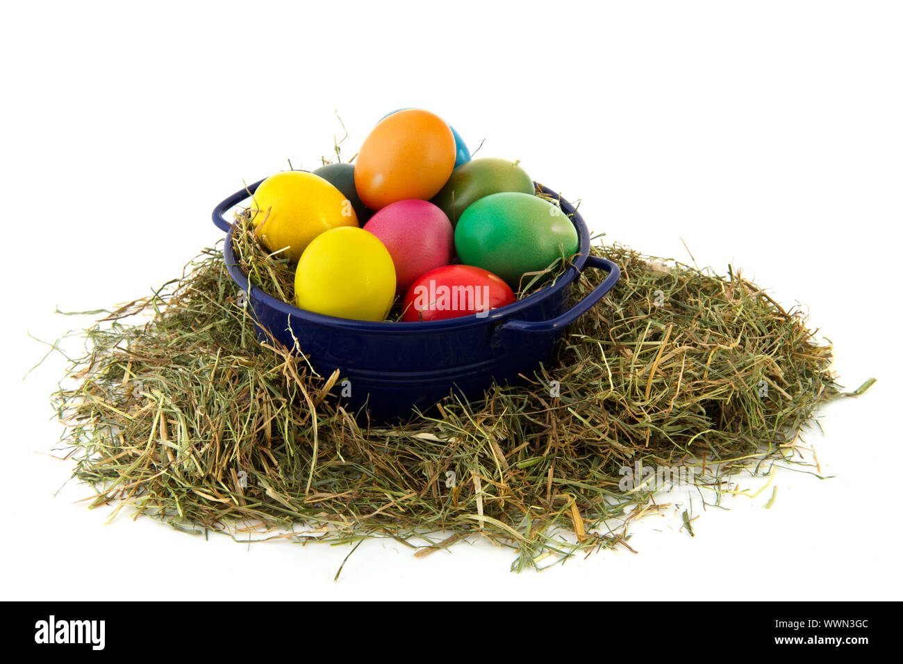 Blue bucket with straw and colorful painted easter eggs Stock Photo