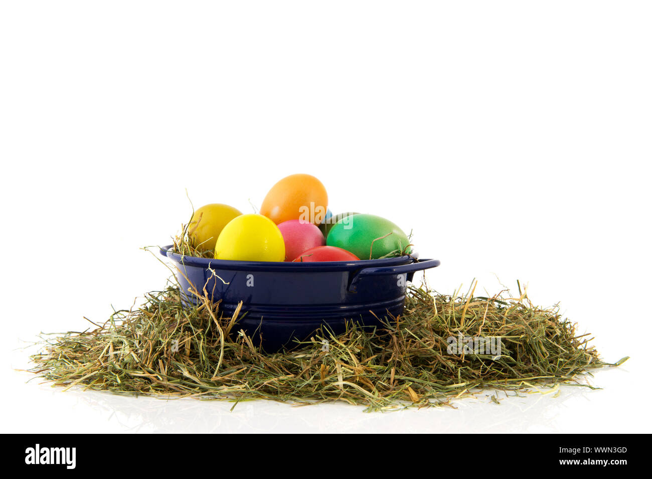 Blue bucket with straw and colorful painted easter eggs Stock Photo