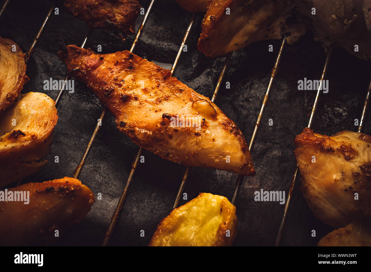 Roasted Chicken Slices and Potatoes on Stainless Steel Cooking Grid. Grilled Chicken Breast with Slices Made for Marinade to Penetrate the Meat Better Stock Photo