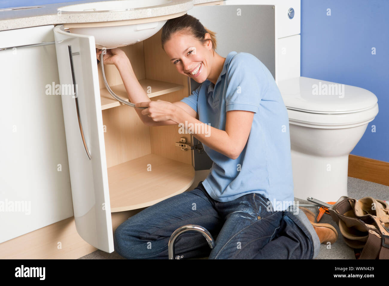 Plumber working on sink smiling Stock Photo
