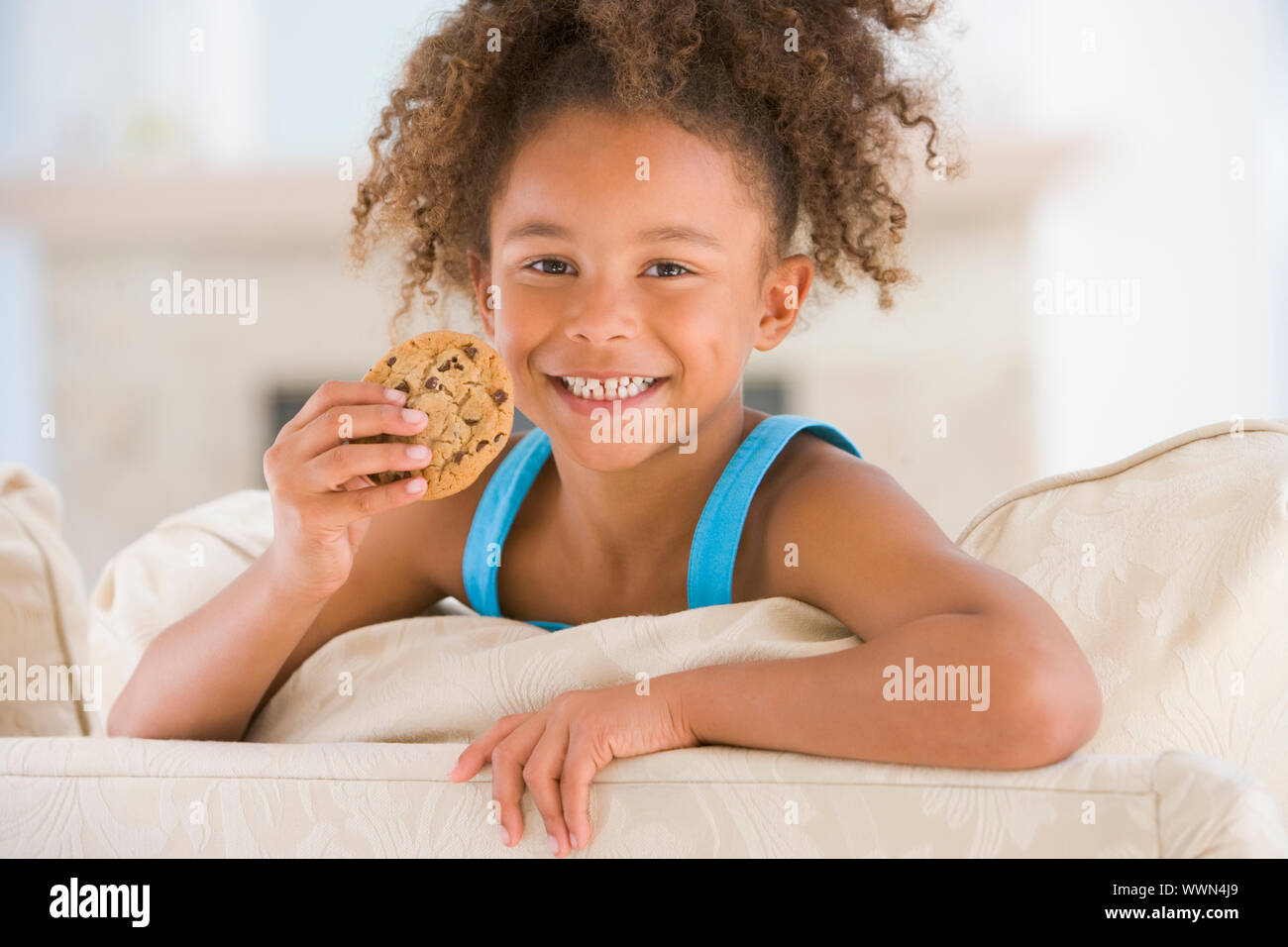 Young girl eating cookie in living room smiling Stock Photo Alamy