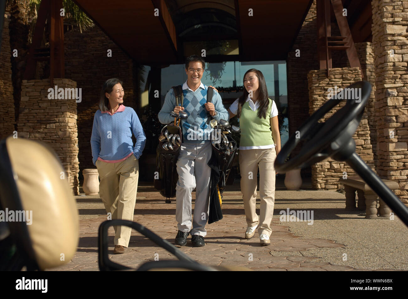 Man Carrying Girlfriend's Golf Clubs to Golf Cart Stock Photo