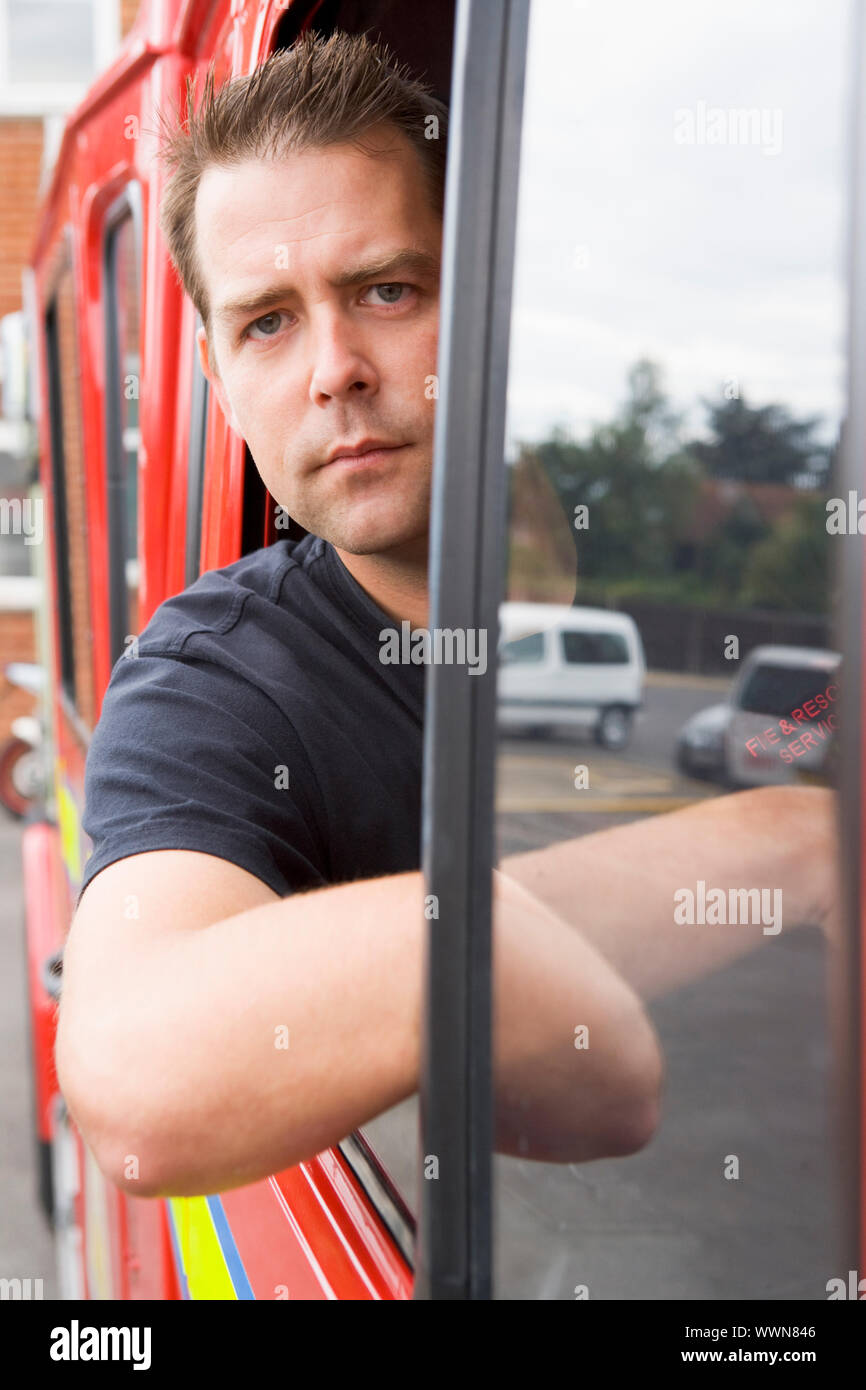 Male firefighter sitting in the cab of a fire engine Stock Photo