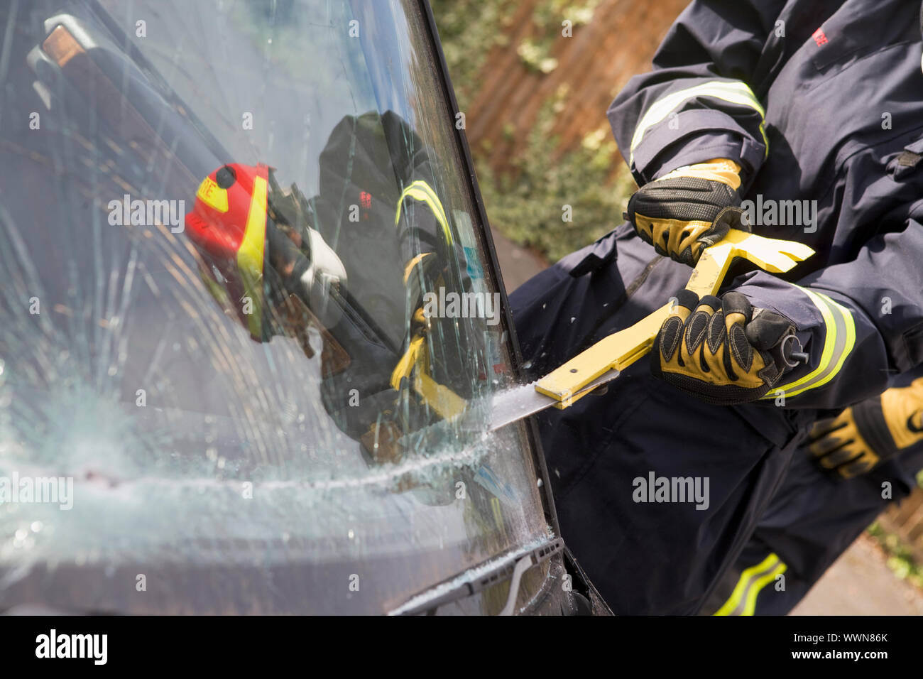 Firefighters breaking a car windscreen to help a car crash victi Stock Photo