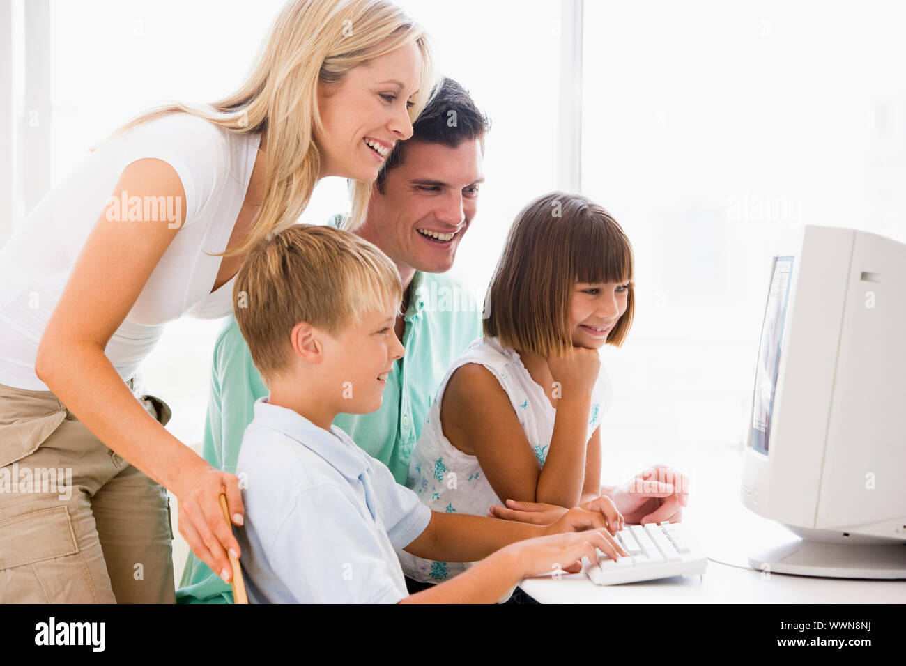 Family in home office using computer smiling Stock Photo - Alamy