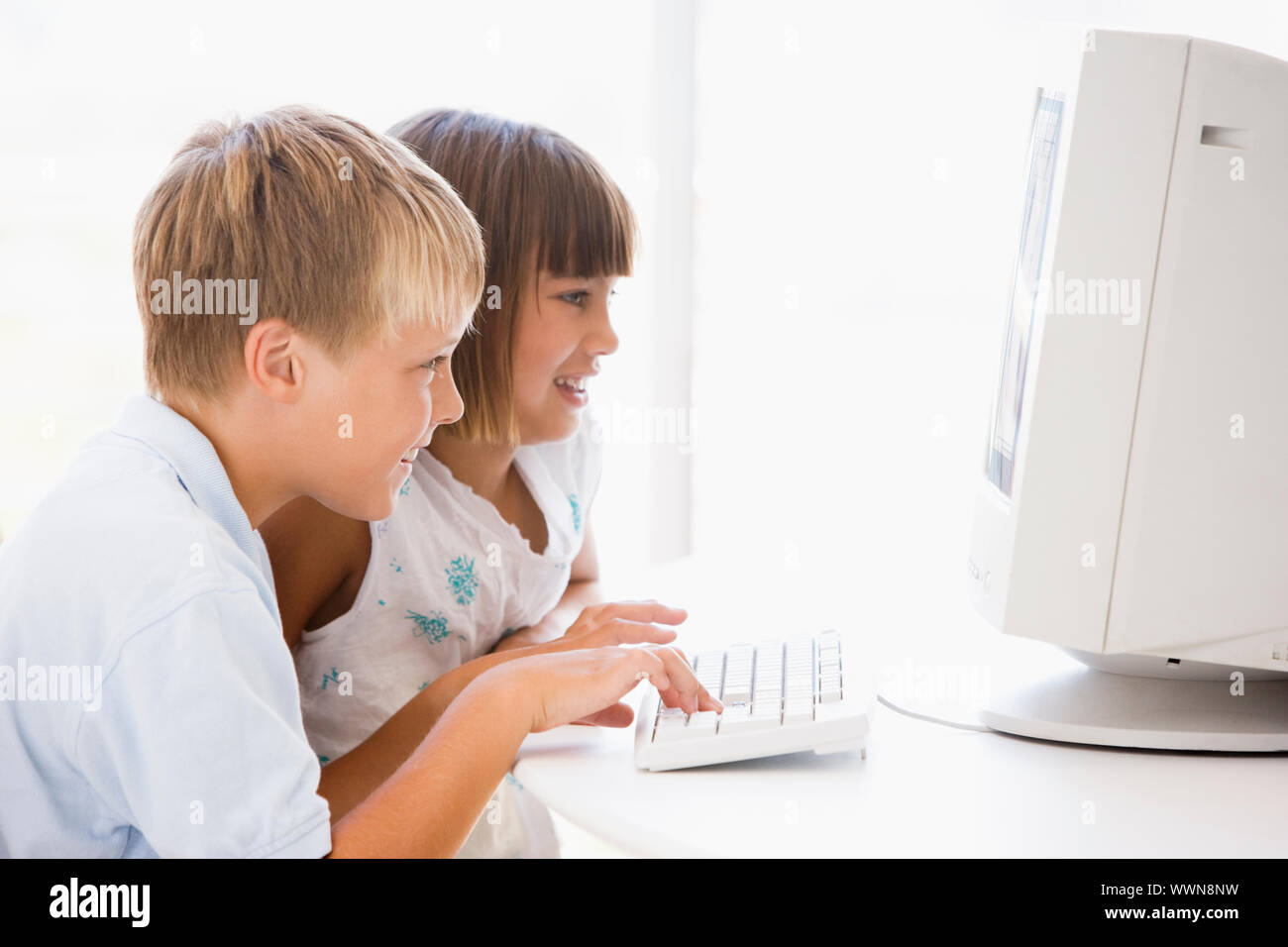 Two young children in home office with computer smiling Stock Photo - Alamy