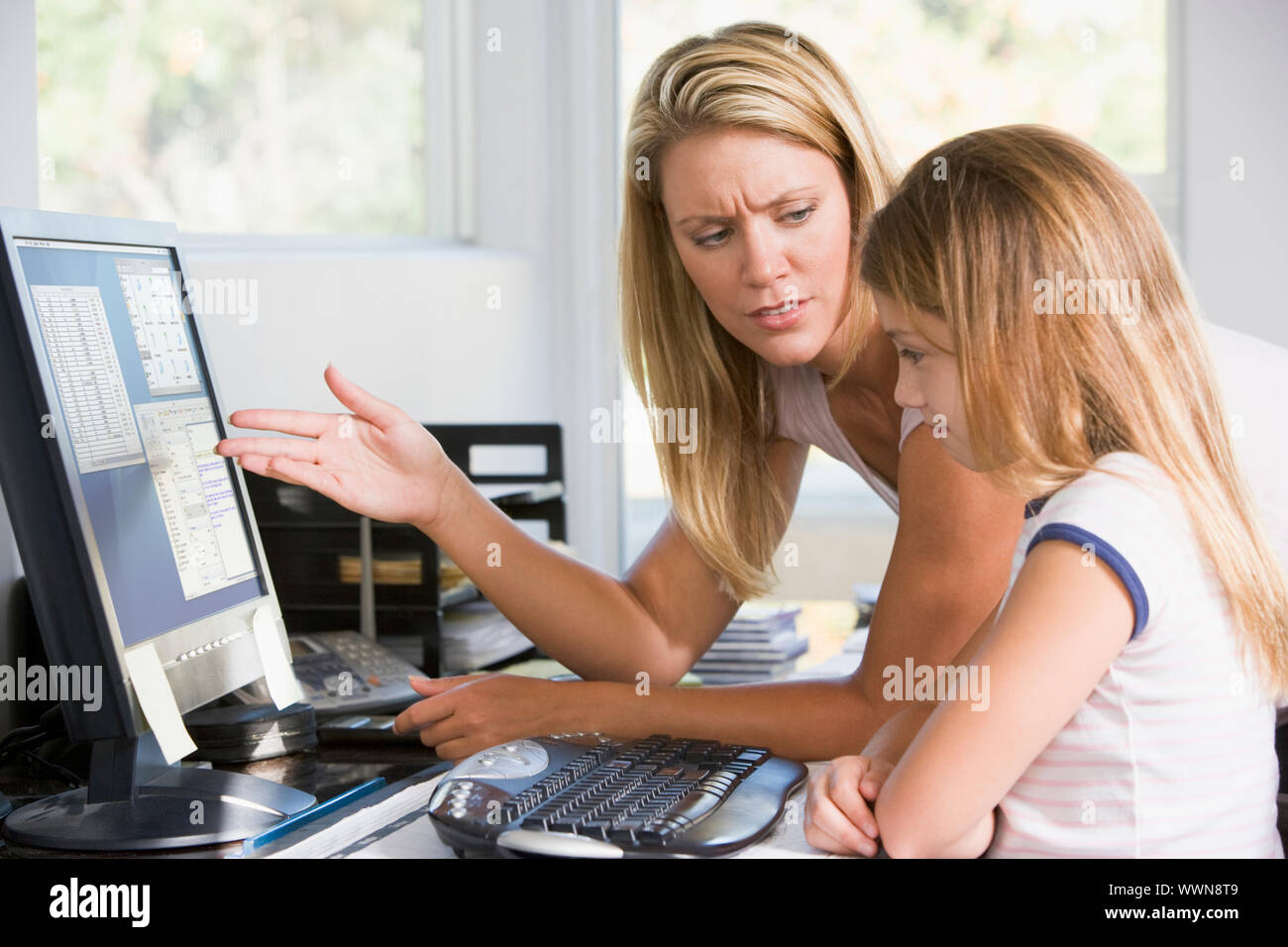 Woman and young girl in home office with computer looking unhapp Stock Photo