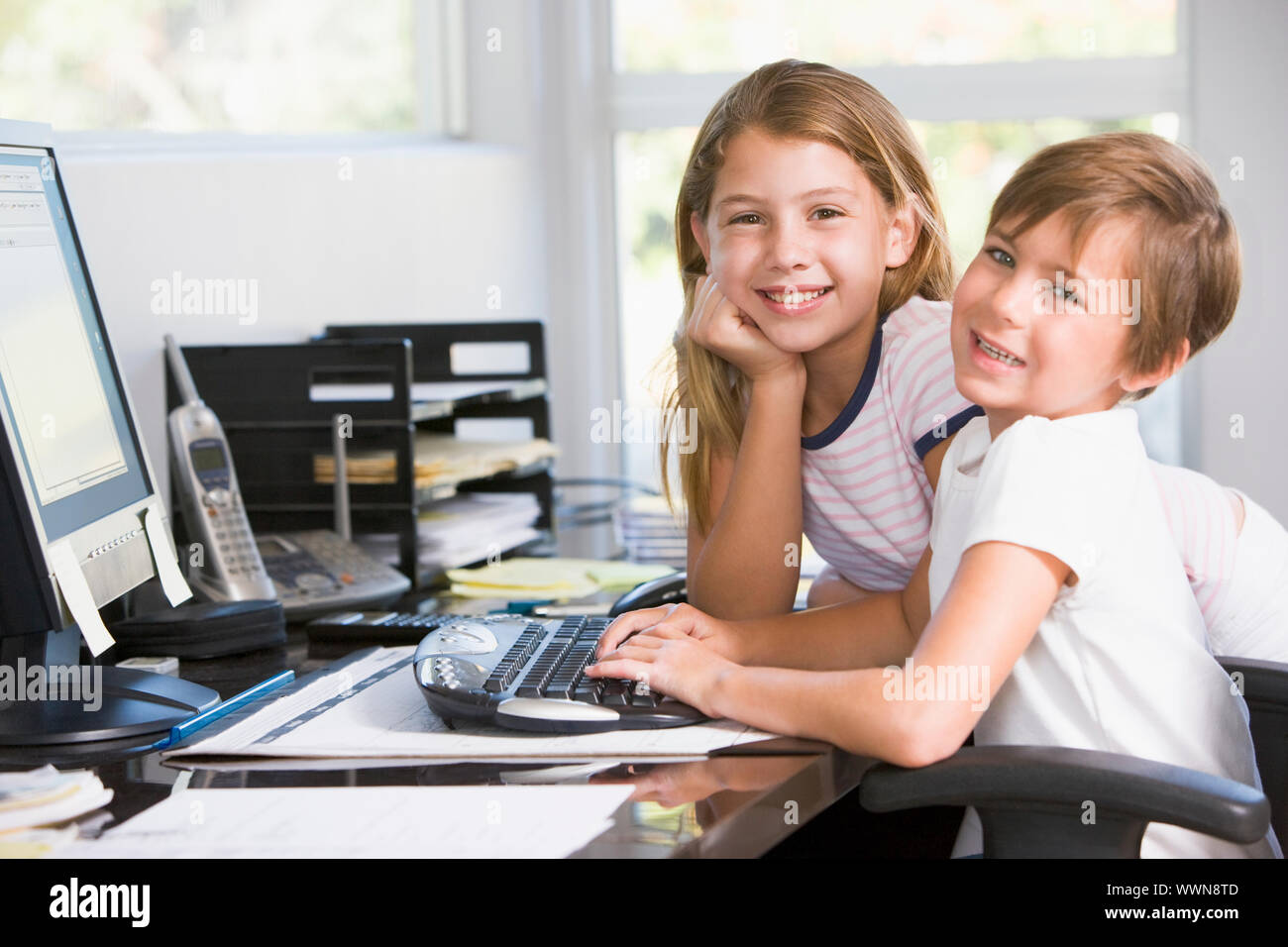 Young boy and young girl in home office with computer smiling Stock ...