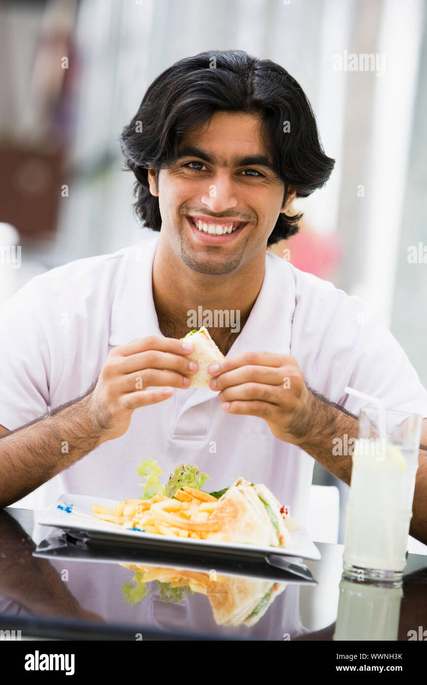 Man at restaurant eating sandwich and smiling Stock Photo