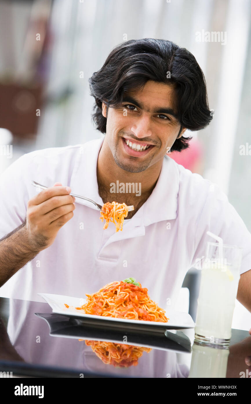 Man at restaurant eating sandwich and smiling Stock Photo