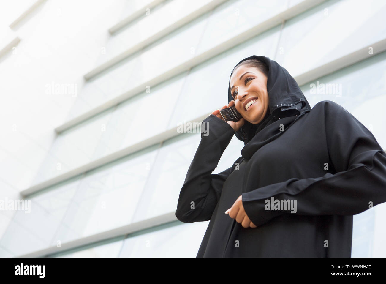 Businesswoman outdoors by building using personal digital assistant and smiling Stock Photo