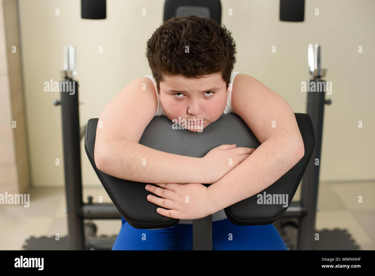 sad tired overweight kid sitting on fitness equipment after hard training Stock Photo