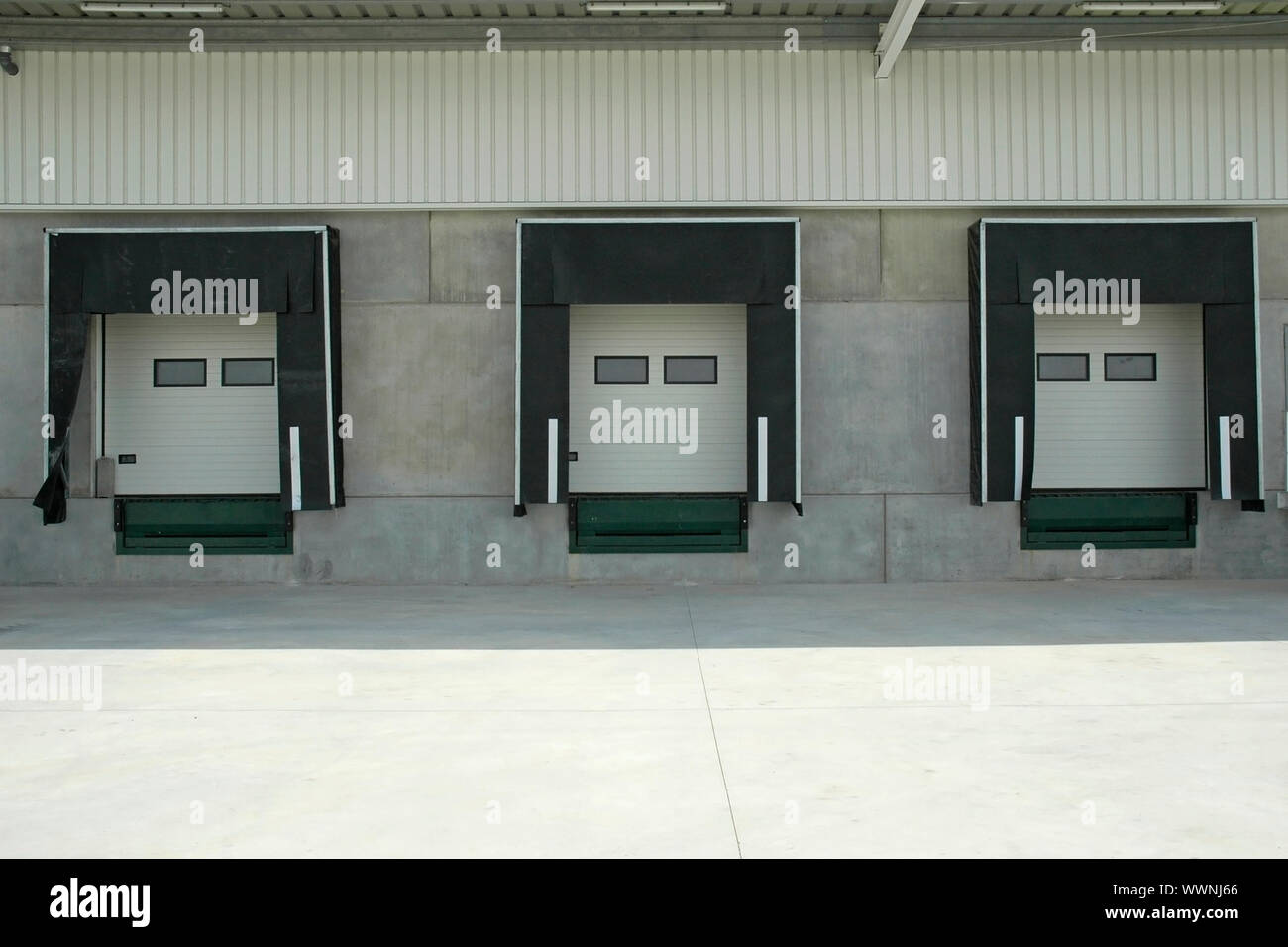 The loading area of a industrial warehouse with several loading bays where truck stop to unlock cargo. Stock Photo