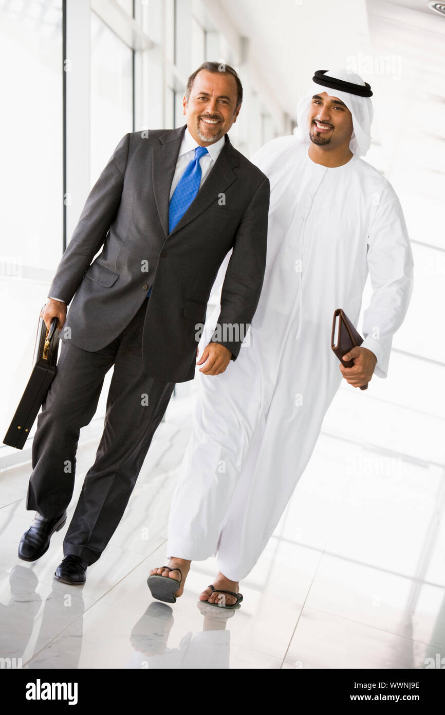 Two businessmen walking in a corridor and smiling Stock Photo - Alamy