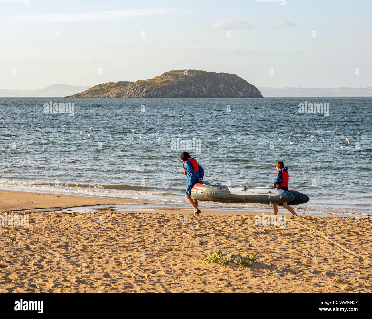 A nman and a boy carry an inflatable dinghy on Milsey Bay beach, North