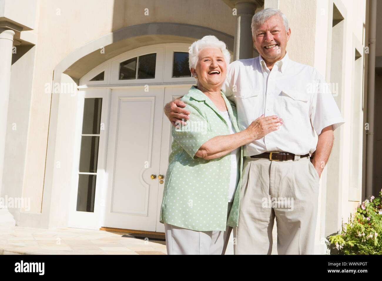 Senior couple standing outside front door of house Stock Photo - Alamy