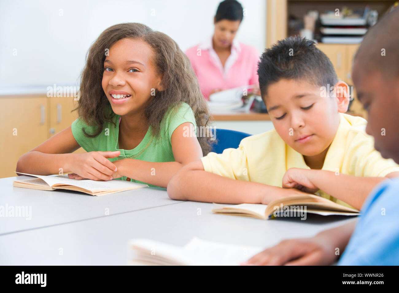Pupils reading whilst sitting at desks Stock Photo