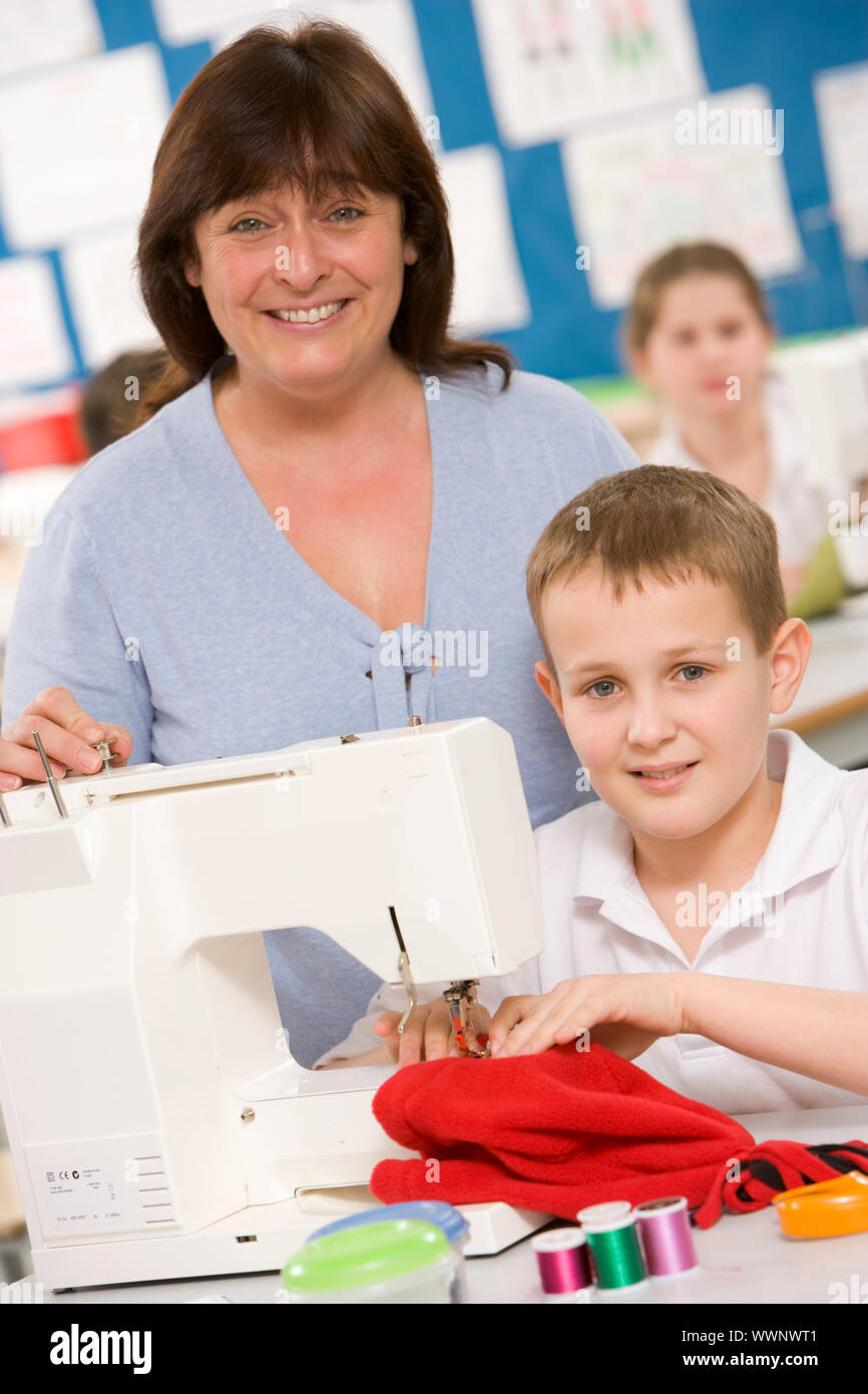 Male student using sewing machine with teacher Stock Photo Alamy