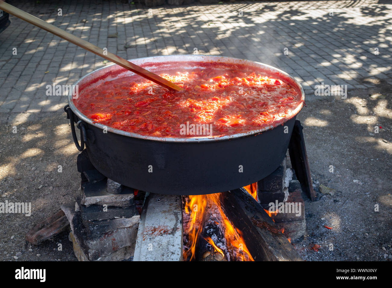 Traditional making tomato paste in boiler with wood fire in the village Stock Photo