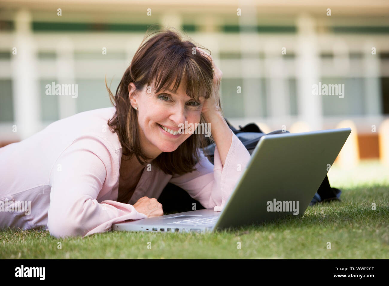 Woman lying on lawn of school with laptop Stock Photo - Alamy