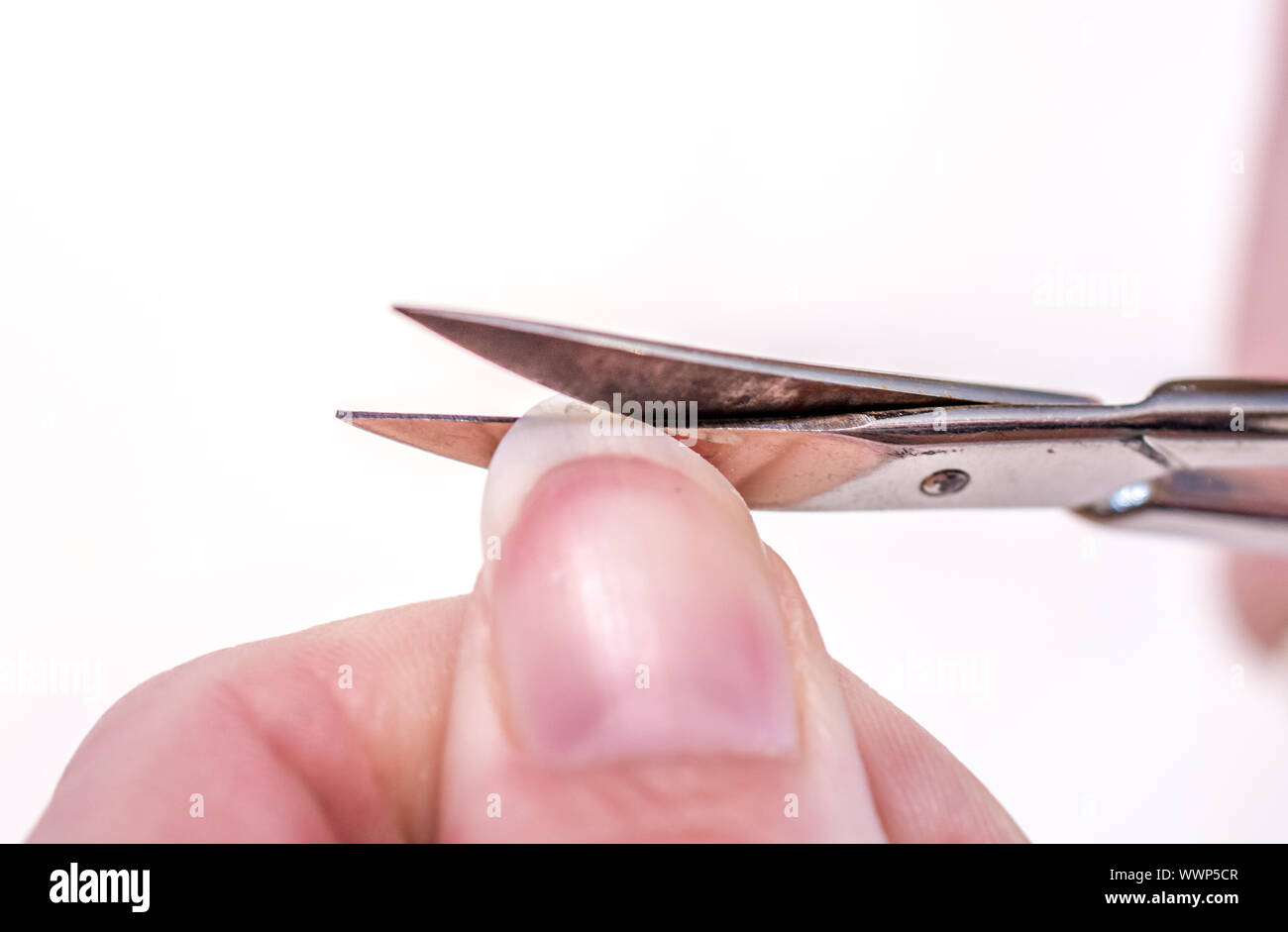 Woman cuts a fingernail with nail scissors Stock Photo