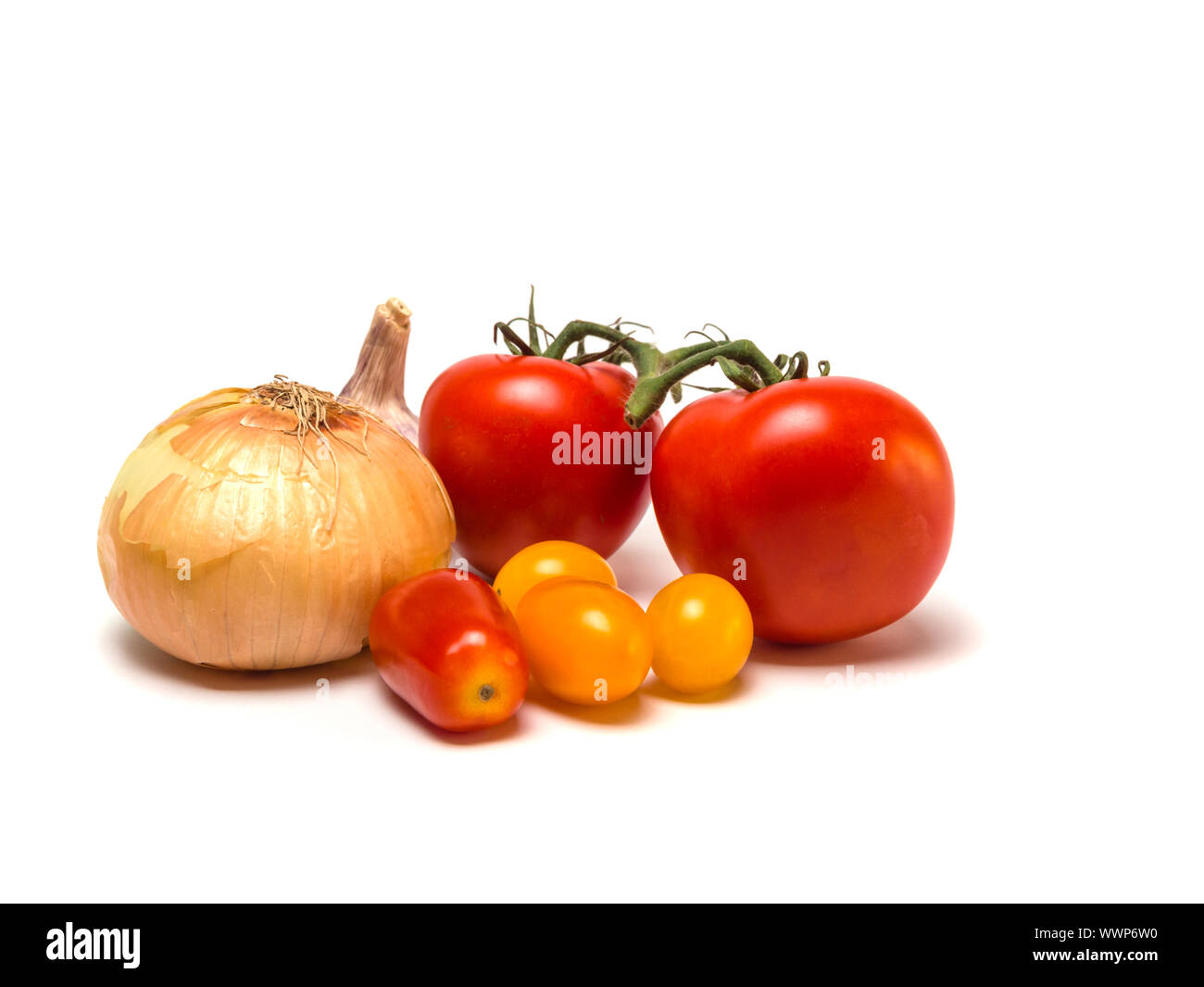 Group of tomatoes of different color and size and an onion an agarlic in the back isolated on white background. Selective focus. Stock Photo
