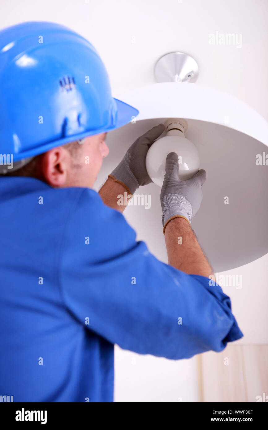 Electrician fitting a ceiling light Stock Photo