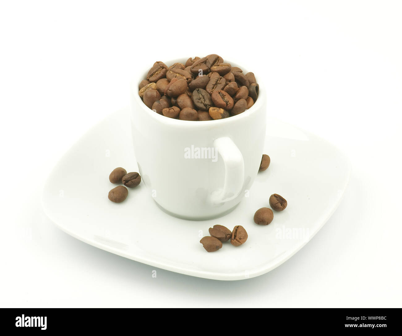 Coffee cup overflowing with dark roasted coffee beans isolated on white backgrounds Stock Photo