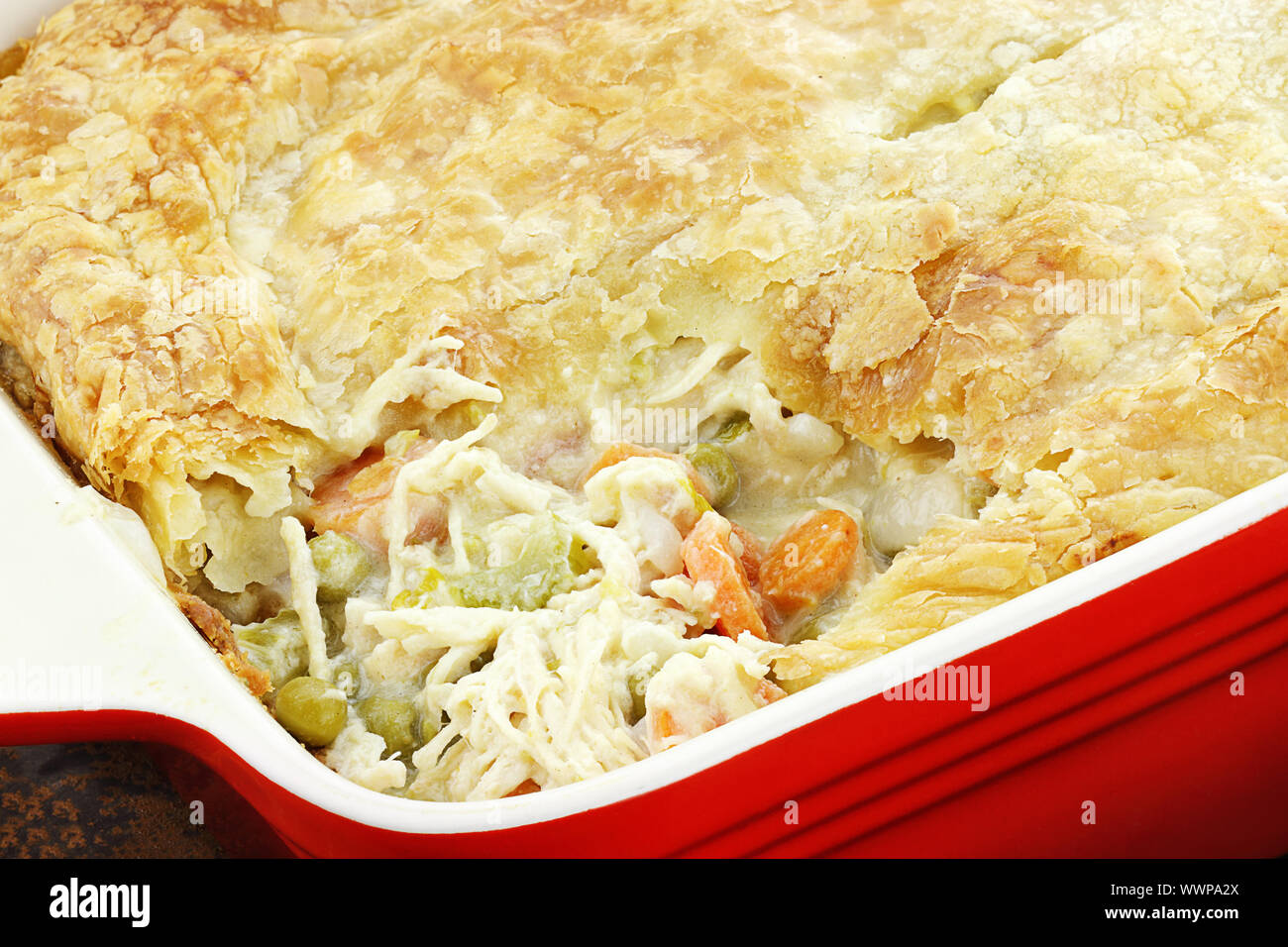 Above view of fresh Chicken Pot Pie with wooden spoon. Section of pot pie removed to reveal chicken, carrots and peas. Stock Photo