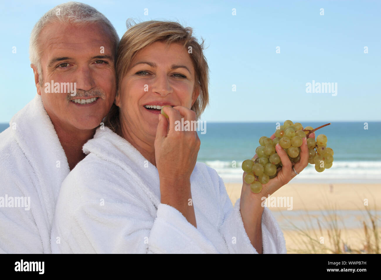 Couple eating grapes for breakfast on the beach Stock Photo Alamy