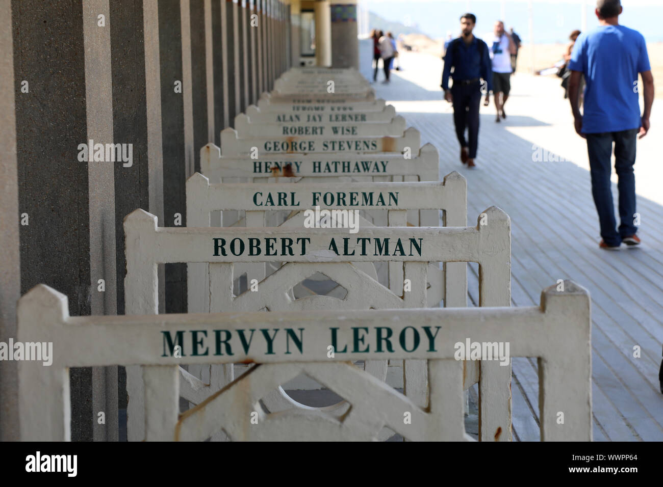 Deauville / France – September 14, 2019: Pedestrians walk along the Promenade des Planches, where names of film stars who have visited are painted out Stock Photo