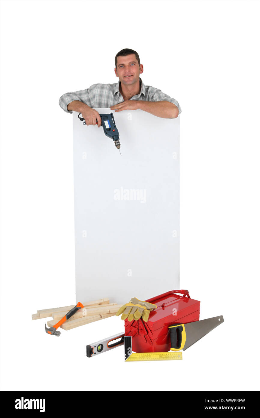 Man holding drill next to blank advertising panel Stock Photo