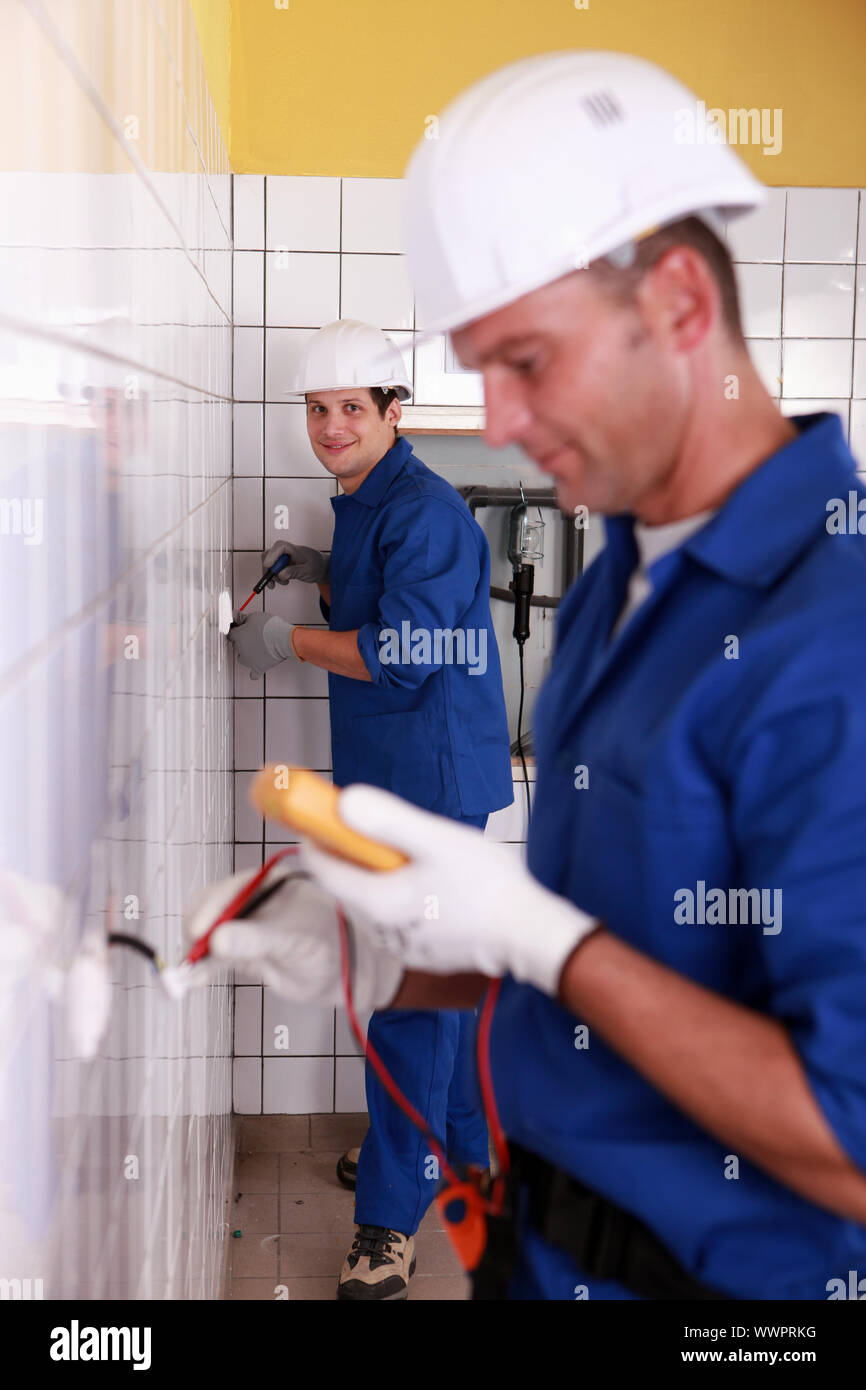 Electricians working in a tiled room Stock Photo