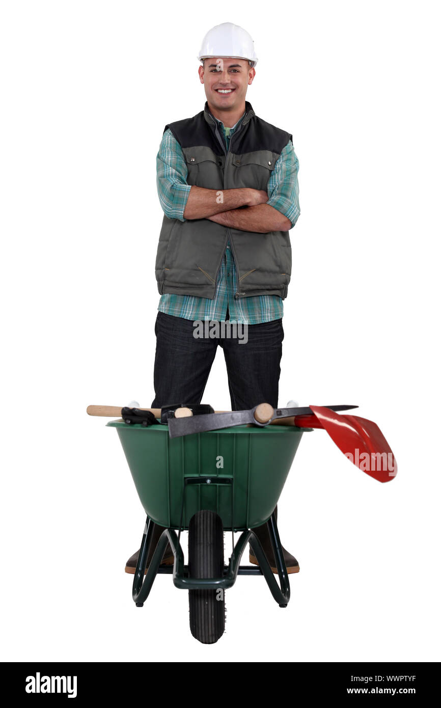 Man stood with wheelbarrow full of tools Stock Photo