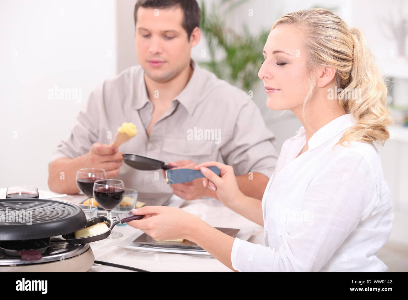 Two friends eating raclette Stock Photo - Alamy